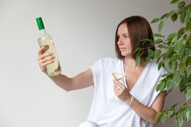 Sommelier de menina morena caucasiana segurando uma taça de vinho branco