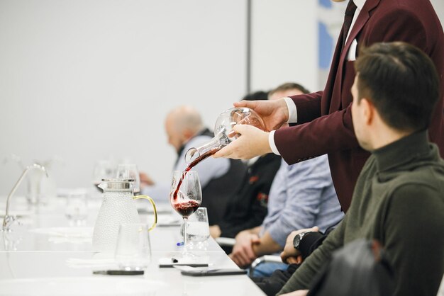 Foto sommelier experiente derramando vinho vermelho do decantador para o copo durante bebidas alcoólicas