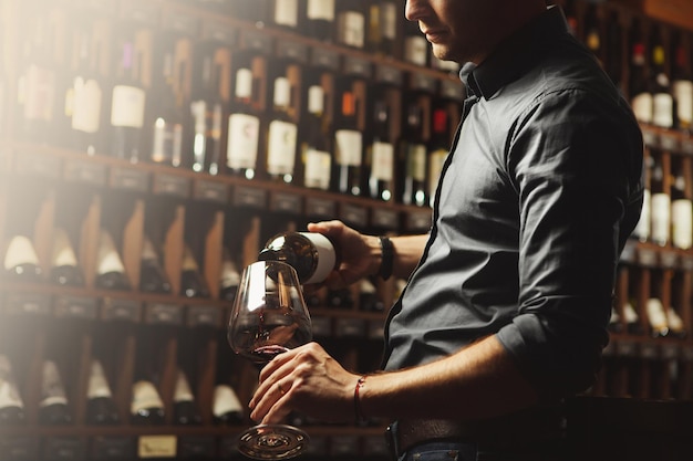 Sommelier masculino vertiendo vino tinto en copas de vino de tallo largo Camarero con botella de bebida alcohólica