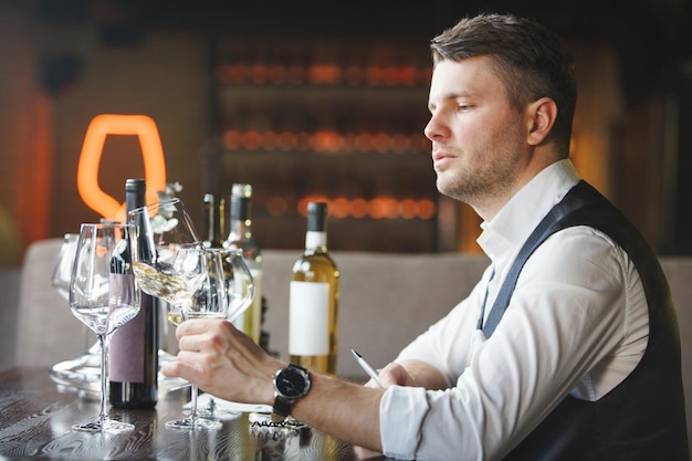 Sommelier mira la copa de vino blanco en la mesa del restaurante