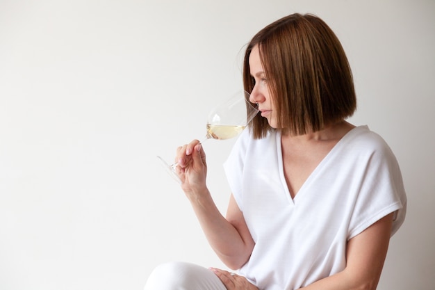 Sommelier de niña morena caucásica sosteniendo una copa de vino blanco