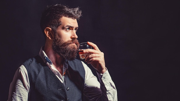Sommelier prova bebida cara Empresário barbudo de terno elegante com copo de uísque