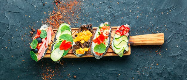 Foto sommer bruschettas oder canape mit frischkäse, speck und gemüse. traditionelle italienische bruschetta