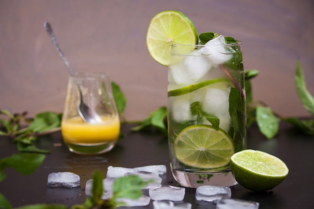 Sommer-Coctail-Mojito mit Eis, Minze, Limette auf grauem Hintergrund.