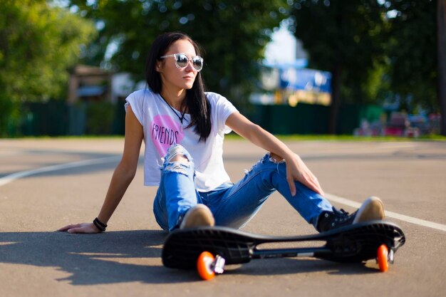 Sommer das Mädchen im Park, das ein Skateboard fährt