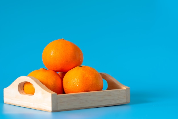 Foto sommer der orange frucht im hölzernen kasten auf blauem hintergrund.