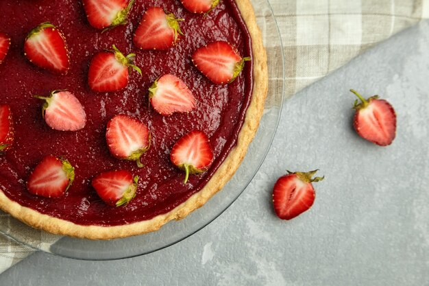 Sommer Erdbeertarte mit frischen Beeren auf Leinenserviette auf grauem Tisch verziert