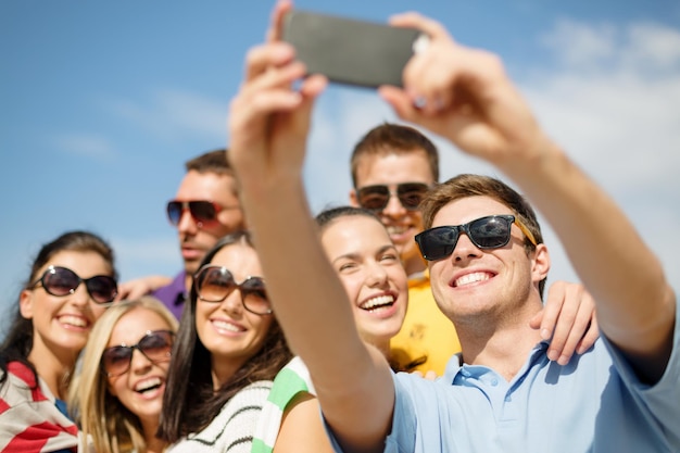 Sommer-, Ferien-, Ferien- und Glückskonzept - Gruppe von Freunden, die mit Smartphone fotografieren