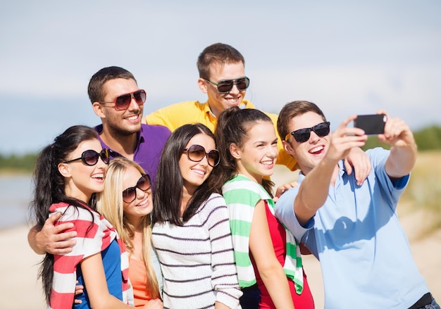 Sommer, Ferien, Urlaub, Konzept der glücklichen Menschen - Gruppe von Freunden, die mit Smartphone fotografieren