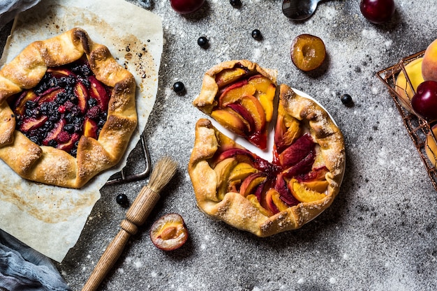 Sommer Galette mit Beeren, Himbeeren, Heidelbeeren, Brombeeren, Äpfeln und knusprigem Zucker vegetarischer Teig. Veganes Essen. Gesundes Essen. Pfirsichkuchen. Torte. Sommeressen, Sommerkuchen auf Pergamentpapier.