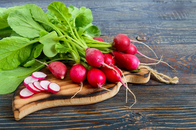 Sommer geernteter roter Rettich. Anbau von Bio-Gemüse. Große Menge rohen frischen saftigen Gartenrettich auf dunklen Brettern bereit zu essen.