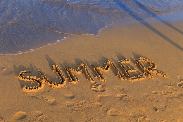 Sommer geschrieben im Sand an einem Strand in der Nähe des Meeres