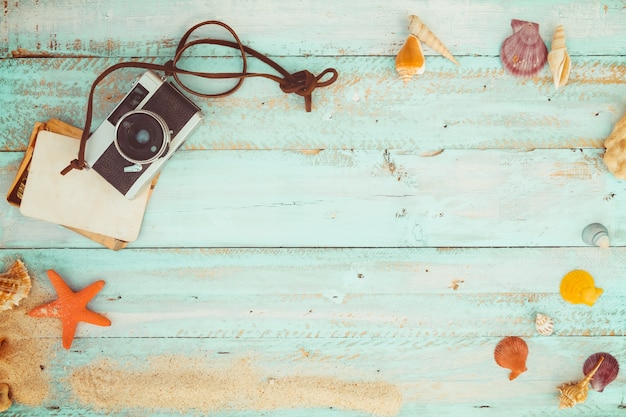 Sommer Hintergrund - Das Konzept der Freizeit Reisen im Sommer auf einem tropischen Strand am Meer. Retro-Kamera mit Seestern, Muscheln, Korallen auf Holz Tisch Hintergrund. Vintage Farbton Styles.