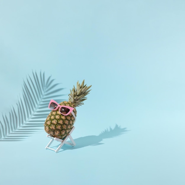 Sommer Hintergrund frische Ananas ruht auf Liegestuhl vor blauem Hintergrund