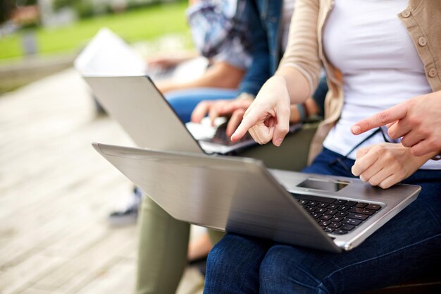 sommer, internet, bildung, campus und personenkonzept - nahaufnahme von studenten oder jugendlichen mit laptops auf dem campus im freien