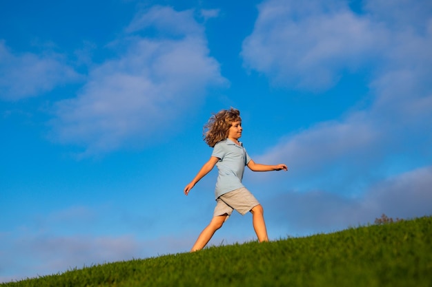 Sommer, Kindheit, Freizeit und Menschenkonzept. Glücklicher kleiner Junge, der auf grünem Sommerfeld geht. Aktivitäten für Kinder in der Natur.