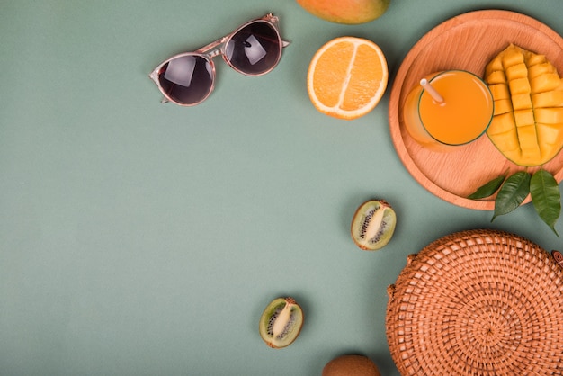 Foto sommer komposition. sonnenbrille mit mango, orange, kiwi auf grünem hintergrund