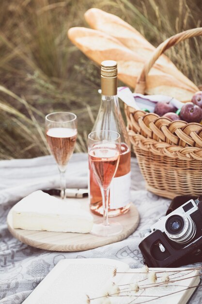 Sommer - Provenzalisches Picknick auf der Wiese. Baguette, Wein, Gläser, Trauben, Käsebrie, Baguette im Korb