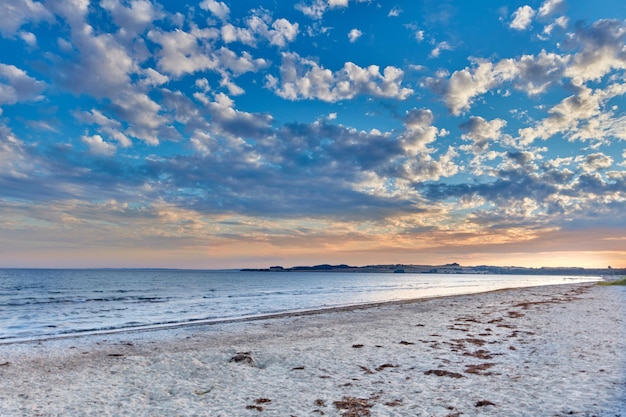 Sommer Sonnenuntergang Blick auf leeren ruhigen Strand bei Ebbe Naturlandschaft einer Küste mit einem bewölkten blauen Himmel über dem Horizont Seaside Szene von Gezeiten und Strömungen an einem schönen Strandtag