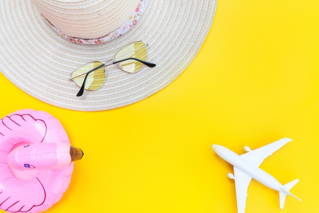 Sommer strand zusammensetzung. minimale einfache flache lage mit ebenem sonnenbrillenhut und aufblasbarem flamingo lokalisiert auf gelbem hintergrund. urlaubsreise abenteuer konzept. kopierbereich der draufsicht.