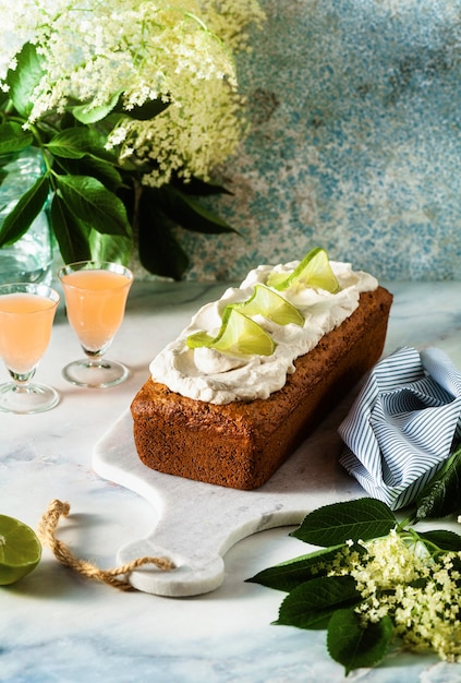 Sommer süßer Laib Kuchen auf einem Tisch mit Blumen und einem Getränk in Gläsern. Dessert zum Brunch oder Frühstück am Morgen