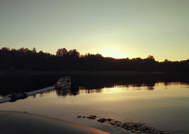 Sommerabendlandschaft mit Seeoberfläche und Fragment des Paddels des aufblasbaren Bootes. Lettland, Osteuropa.