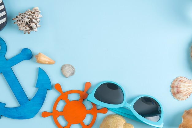 Sommeraccessoires mit Sonnenbrille und Muscheln, auf hellblauem Hintergrund. Ansicht von oben.