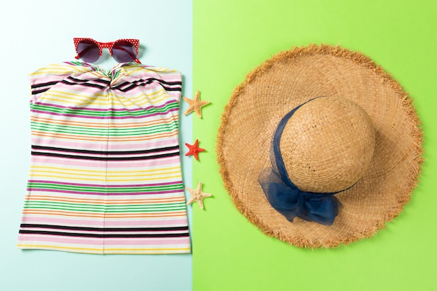 Foto sommeraccessoires mit t-shirt, sonnenbrille, muscheln und strohhut auf der draufsicht im hintergrund.