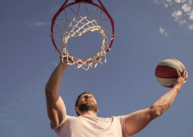 Sommeraktivität starker Mann mit Basketballball auf dem Platz professioneller Basketballspieler