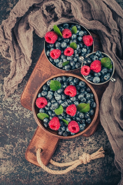 Foto sommerbeeren mischen sich mit himbeere, blaubeere in holz- und metallschalen