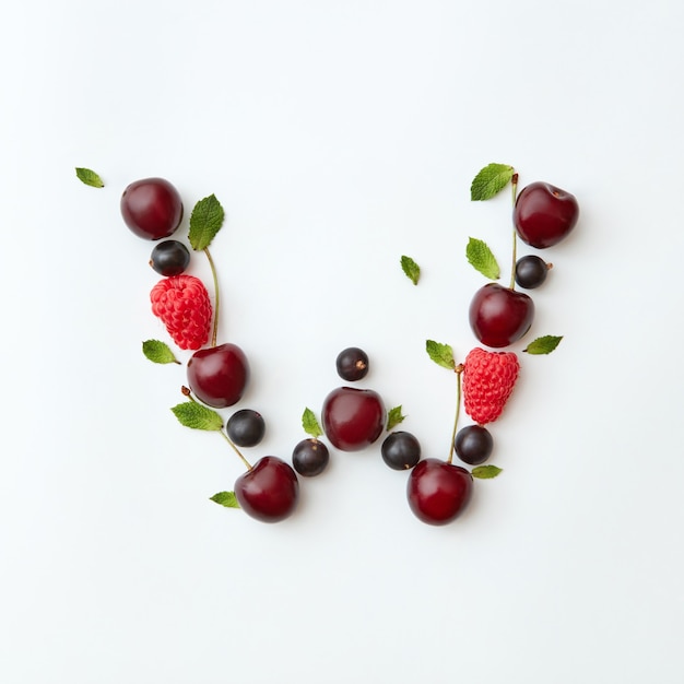 Sommerbeerenmuster des englischen Alphabets des Buchstabens W von natürlichen reifen Beeren - schwarze Johannisbeere