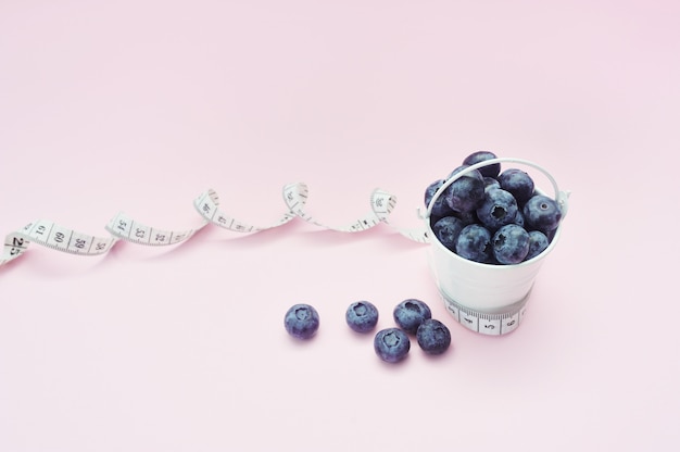 Sommerblaubeeren im Eimer auf rosa Hintergrund