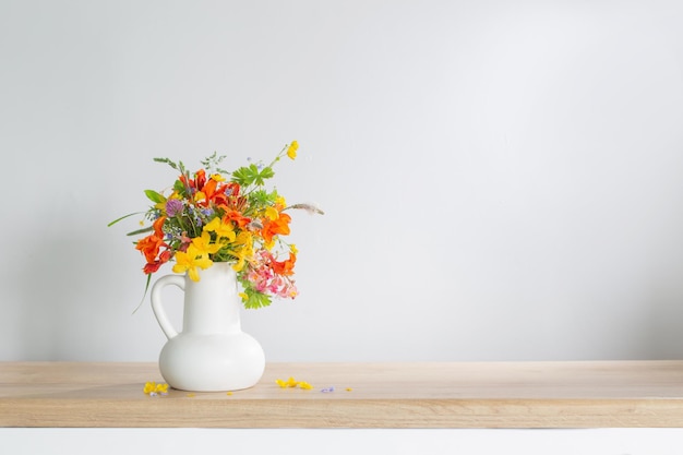 Sommerblumen im weißen Krug auf Holztisch