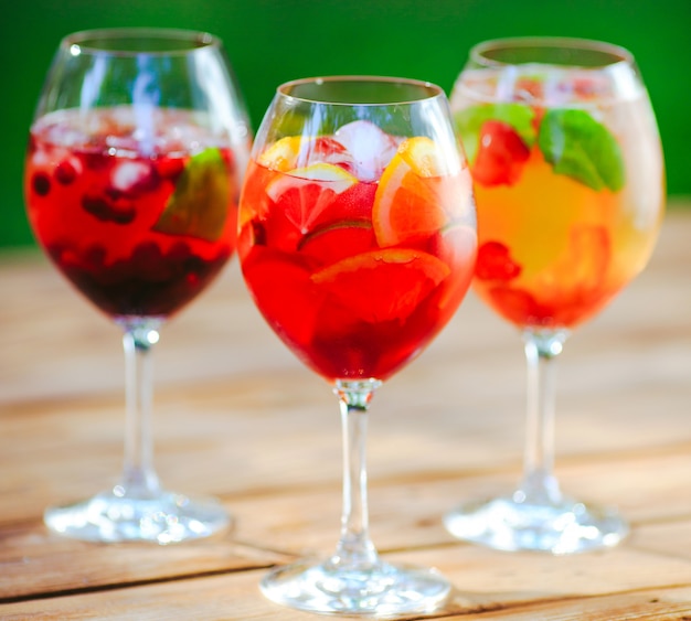 Sommercocktail. Fruchtcocktail auf grün. Zitrusfrüchte, Beeren, Erdbeeren, Blaubeeren, Minze, Eis.