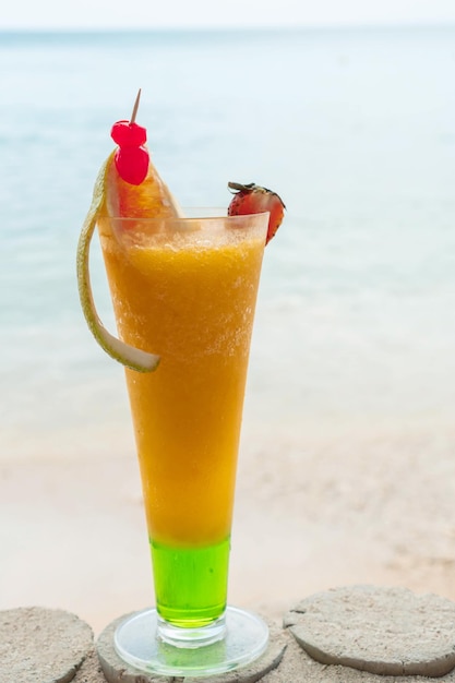 Sommercocktail mit unscharfem Strand im Hintergrund