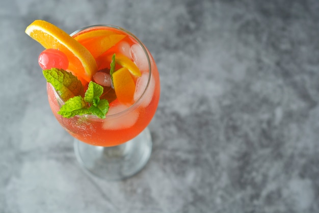 Sommercocktail. Orangensaft mit Minze, Spritze, Fruchtscheiben und Kirsche mit Eis.