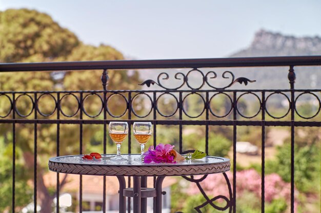 Sommercocktails mit rosa Blüten von Bougainvillea auf Glastisch vor Bergen in der Türkei