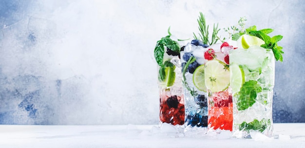 Sommercocktails oder Mocktails und kalte Getränke Erfrischendes Mojito-Getränk mit Heidelbeeren, Brombeeren, Himbeeren und Limettenkräutern und Eis auf grauem Hintergrund