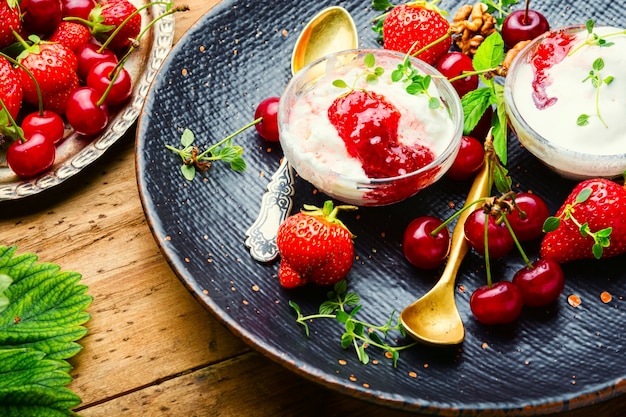 Sommerdessert, Eis mit Erdbeeren und Kirschen. Eis mit Beerenmarmelade auf Holztisch