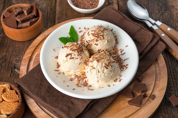 Sommererfrischender Nachtisch auf einer braunen Wand. Eiscreme mit Schokolade und Keksbrösel. Seitenansicht, Nahaufnahme.