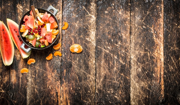 Sommeressen. Obstsalat in einer Schüssel. Auf hölzernem Hintergrund.