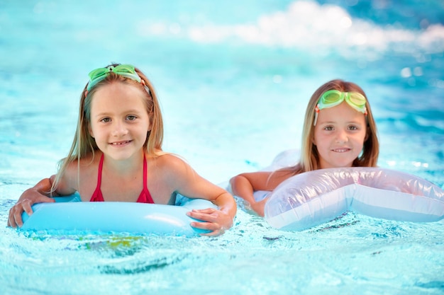 Sommerfelsen Zwei kleine Mädchen, die beim Schwimmen Schlauchboote benutzen