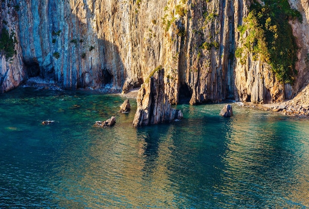 Sommerfelsige Küste (Klippennahaufnahme) und Meerwasser.