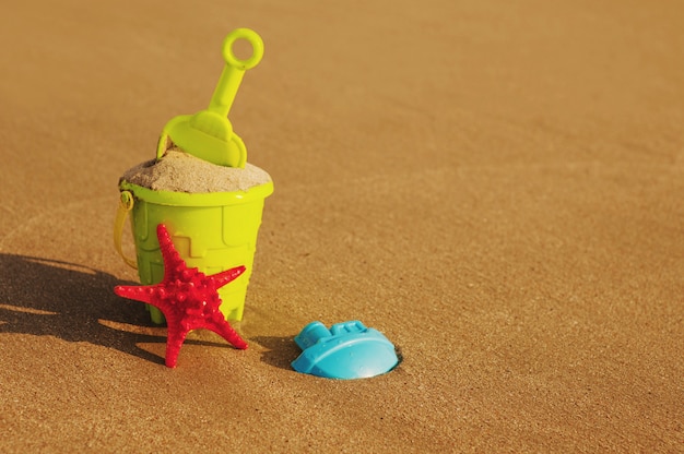 Sommerferien. Eimer und Spaten an einem Sandstrand.