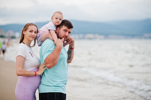 Sommerferien. Eltern und Menschen im Freien mit Kindern. Schöne Familienferien. Vater, schwangere Mutter, Tochter am Meersandstrand.