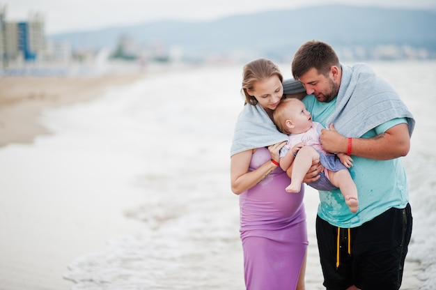 Sommerferien. Eltern und Menschen im Freien mit Kindern. Schöne Familienferien. Vater, schwangere Mutter, Tochter am Meersandstrand.