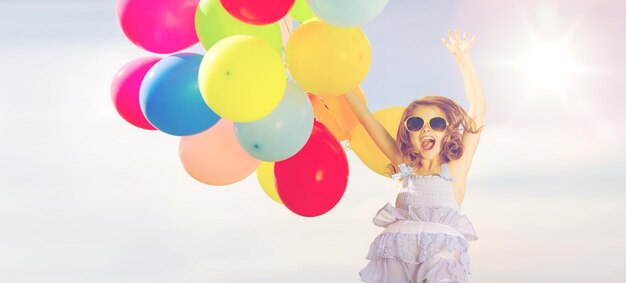 sommerferien, feier, kinder- und menschenkonzept - fröhliches springendes mädchen mit bunten luftballons im freien
