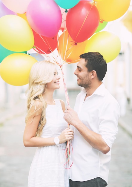 Sommerferien, Feiern und Dating-Konzept - Paar mit bunten Luftballons in der Stadt