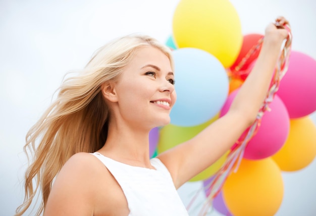 Sommerferien, Feiern und Lifestyle-Konzept - schöne Frau mit bunten Luftballons draußen