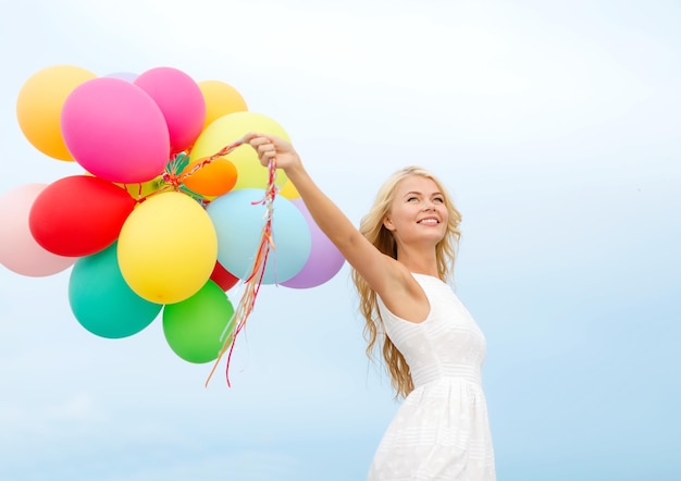 Sommerferien, Feiern und Lifestyle-Konzept - schöne Frau mit bunten Luftballons draußen